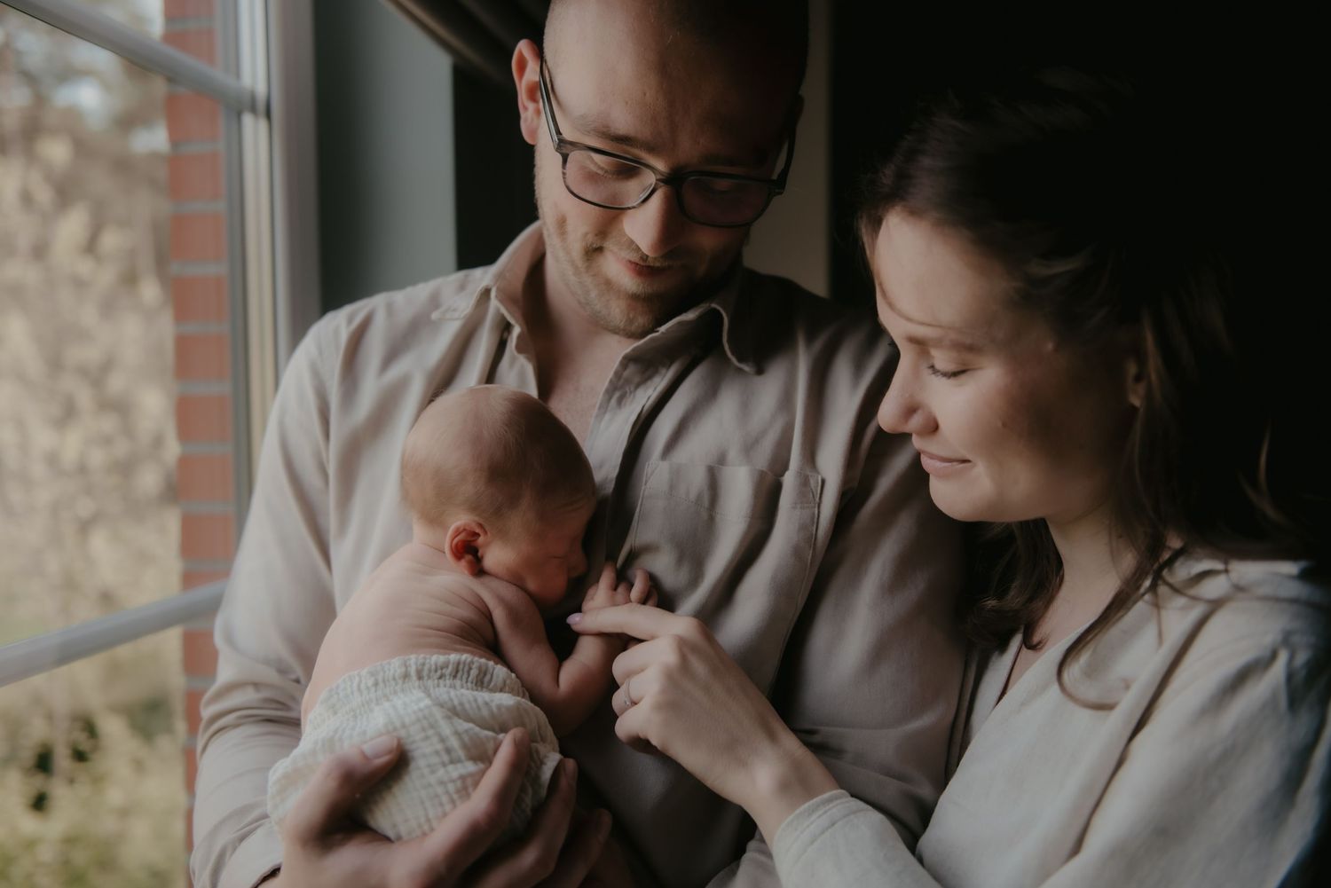 Intimate family moment by window with natural light streaming in.