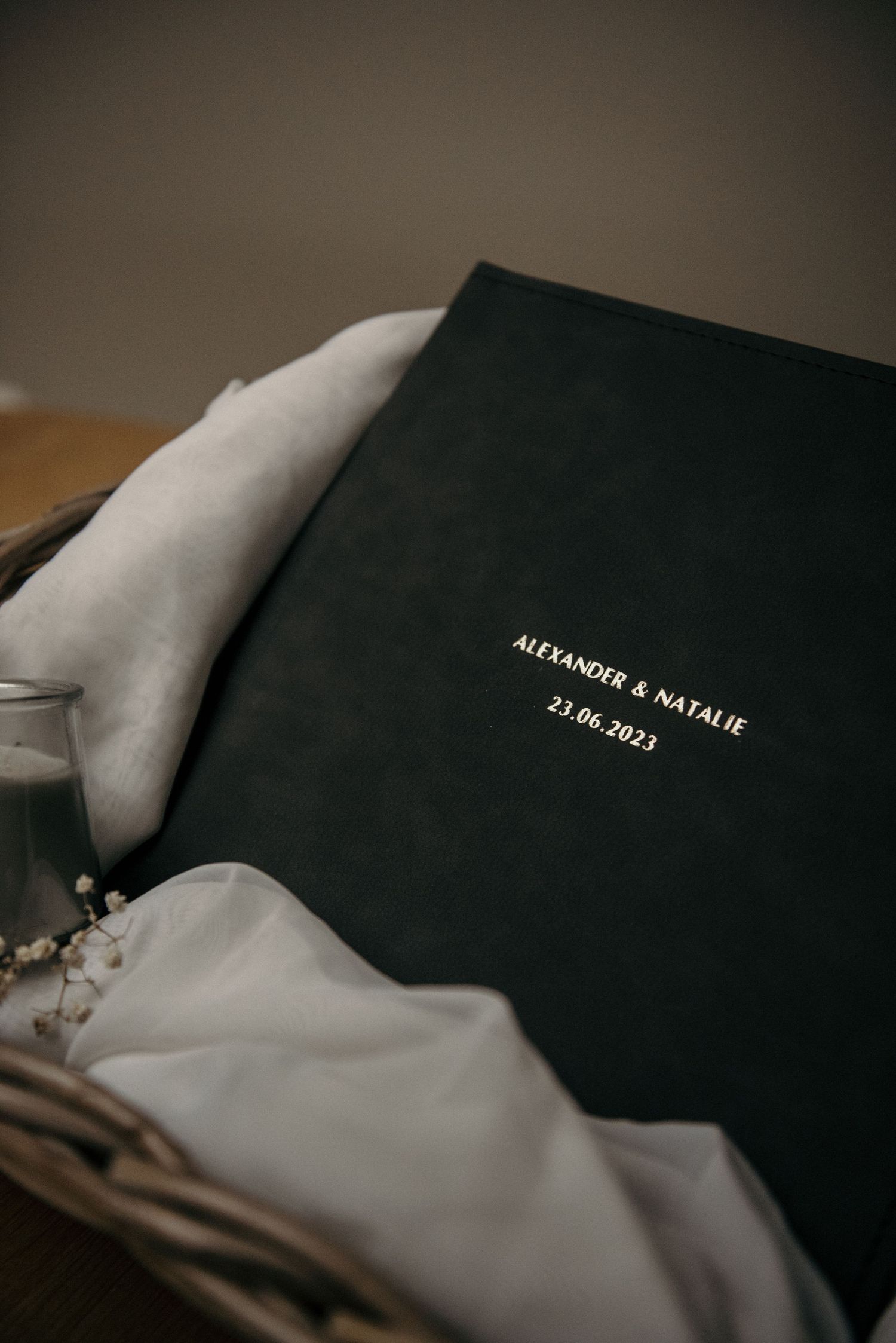 Elegant black wedding album with embossed text on white fabric background.