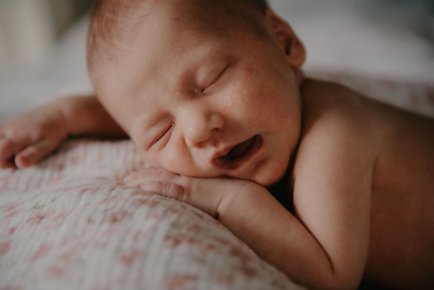 Peaceful sleeping newborn on soft floral patterned bedding.