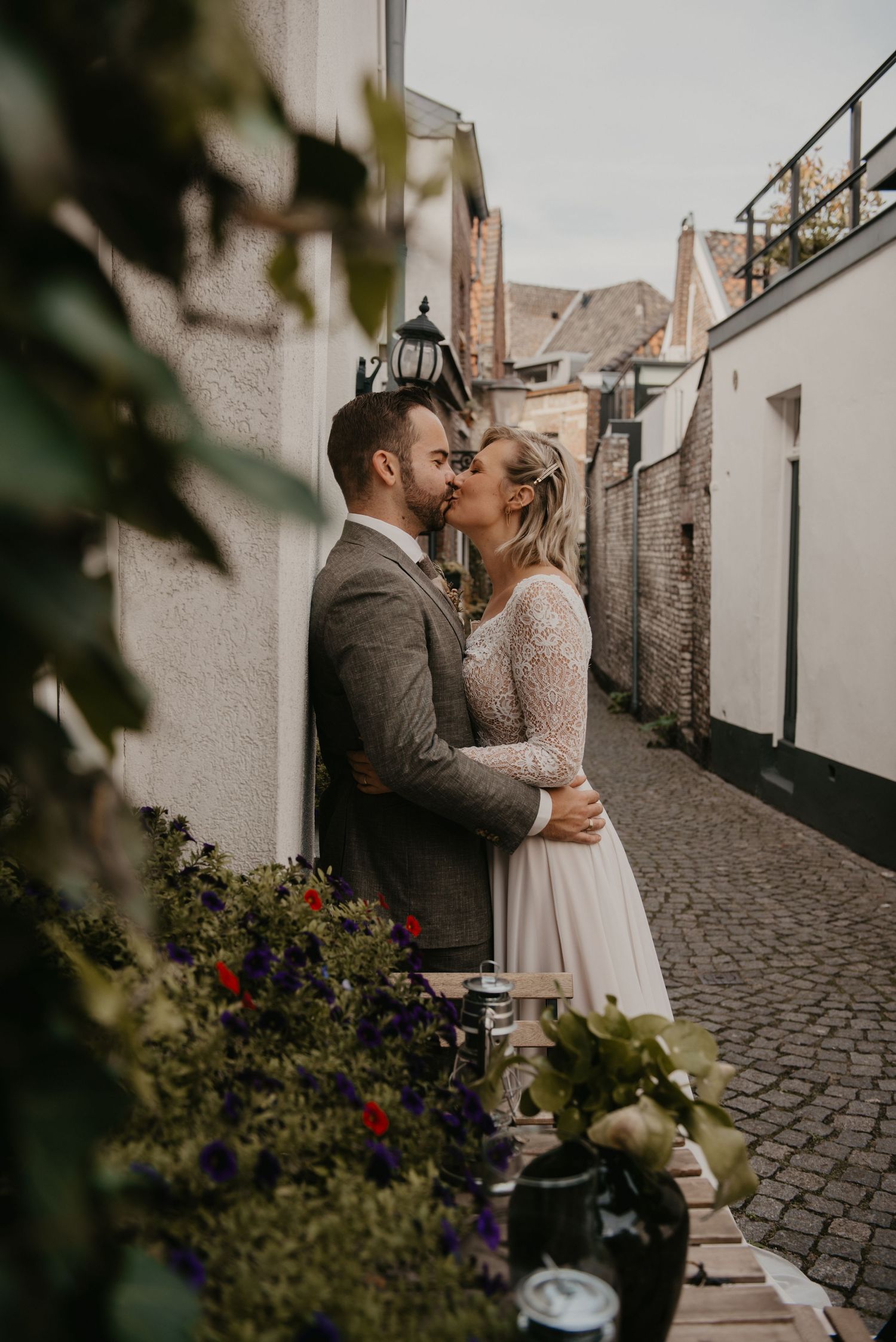 Romantic moment on cobblestone street with flowering bushes.