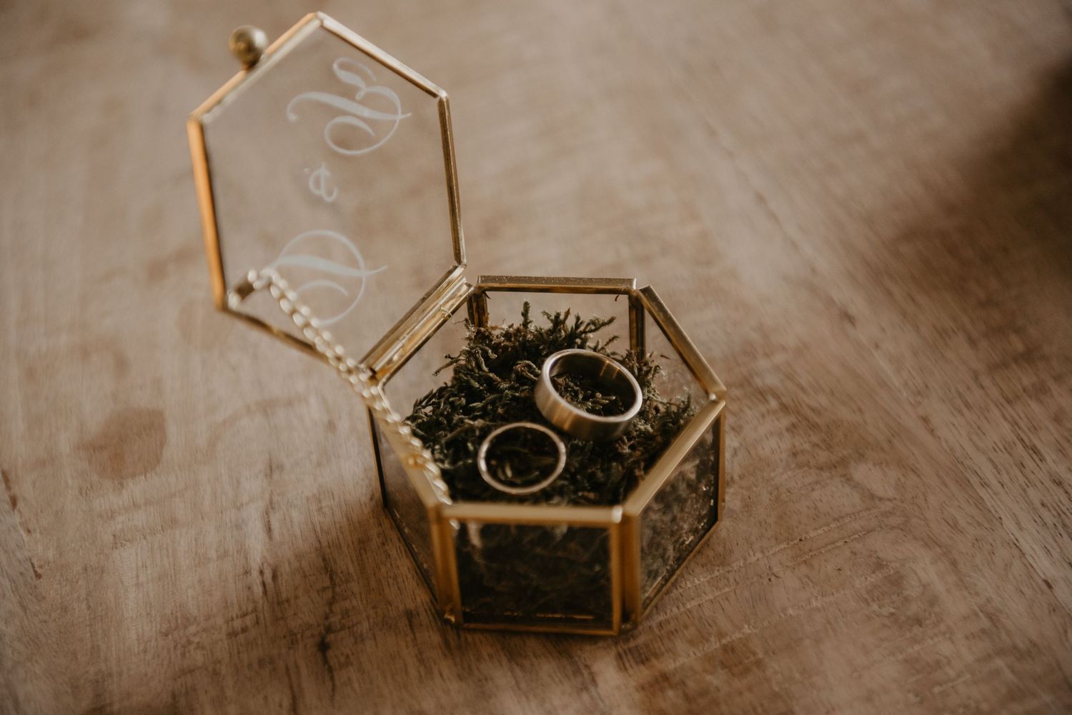 Decorative glass jewelry box on wooden surface in sepia tones.