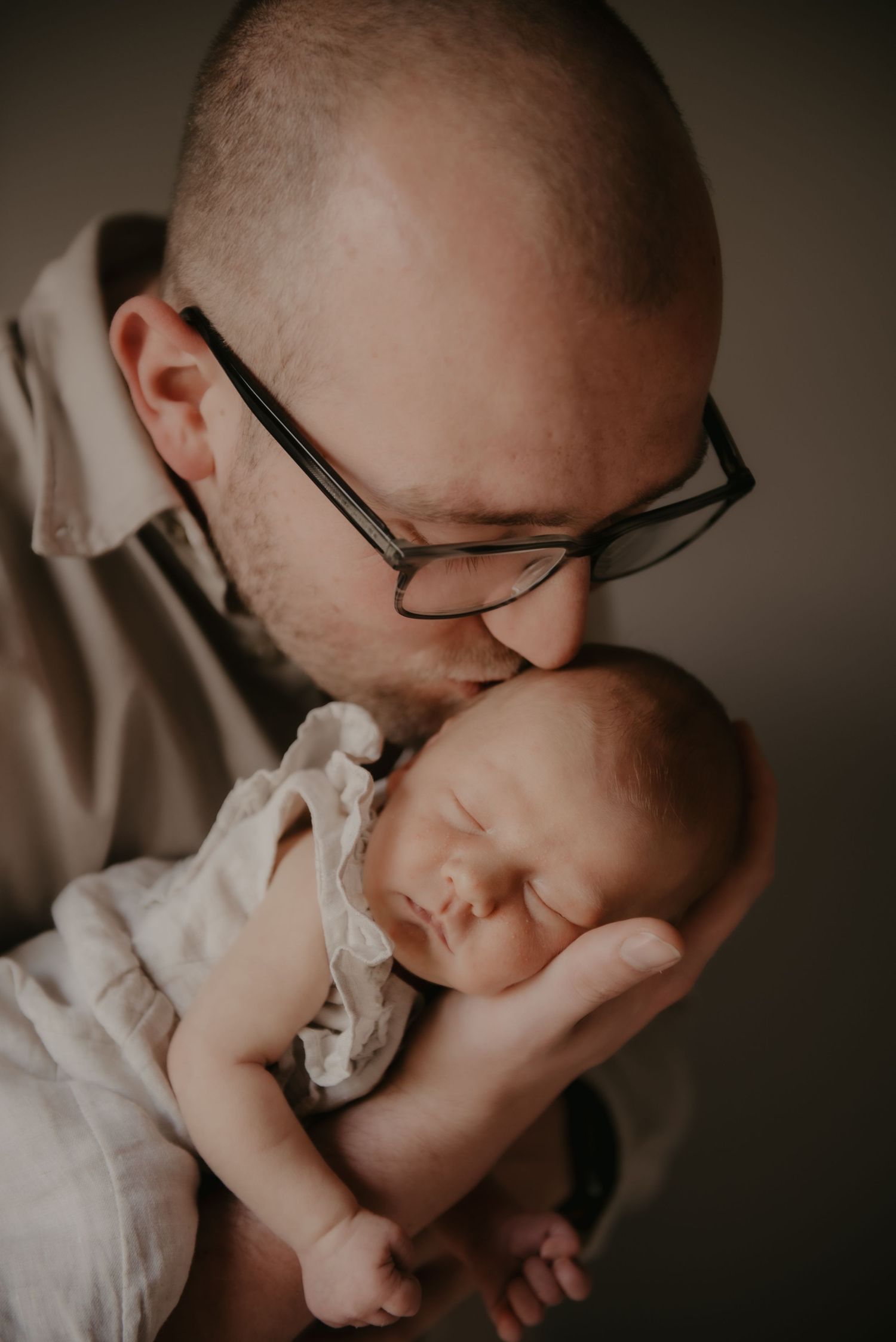 Intimate close-up shots of a newborn baby being held in gentle embrace.