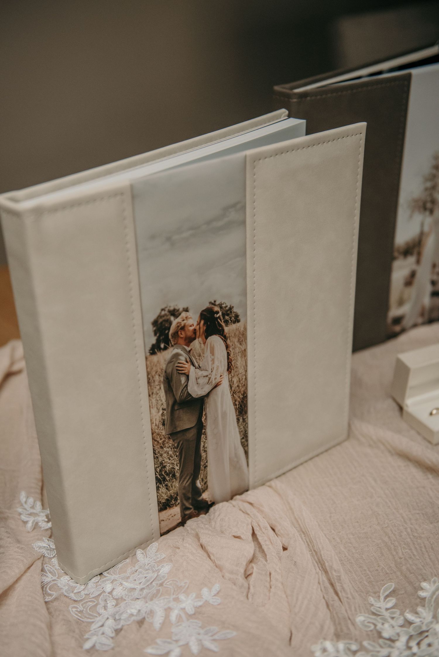 Wedding photo album with delicate lace details on cream-colored fabric.