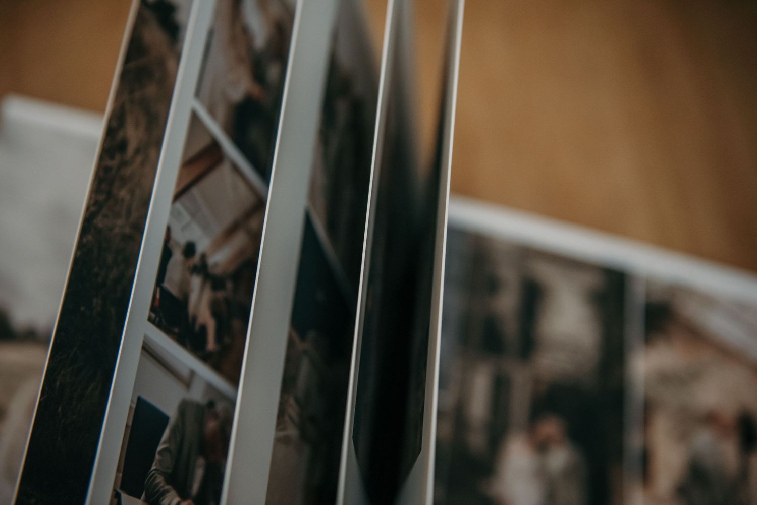 Wedding photo album pages spread out on wooden surface showing black and white photographs.