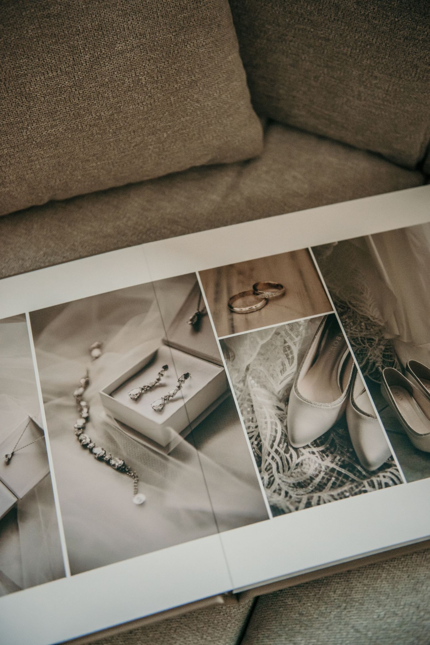 Professional wedding album spread open on grey couch showing multiple images.