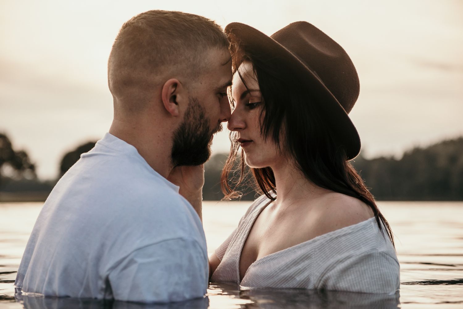 Romantic couple sharing an intimate moment at sunset by the water.