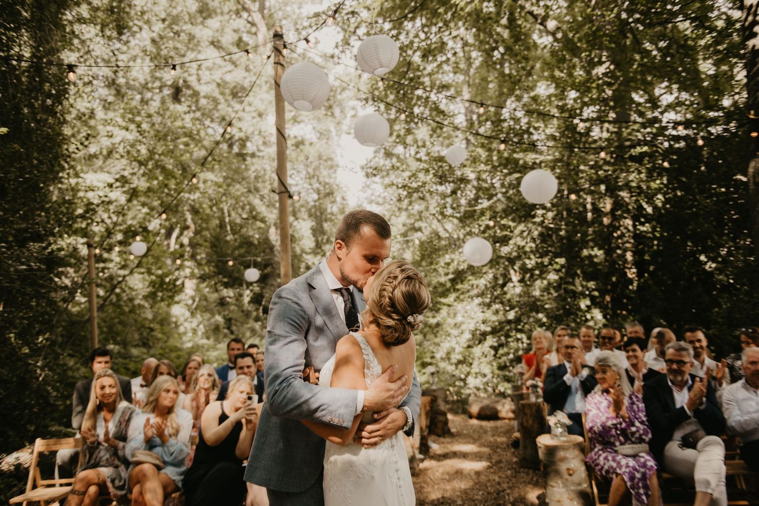 Wedding celebration in a garden setting with hanging lights and natural decor.