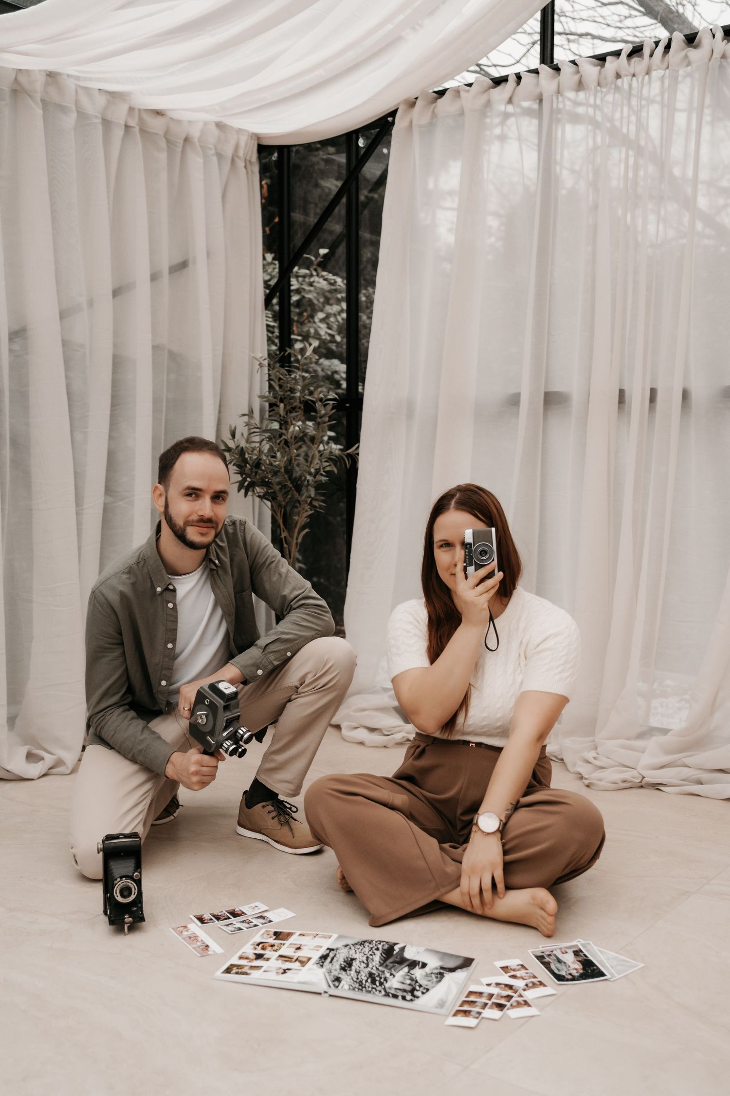 Photographers reviewing prints spread on studio floor with white curtain backdrop.