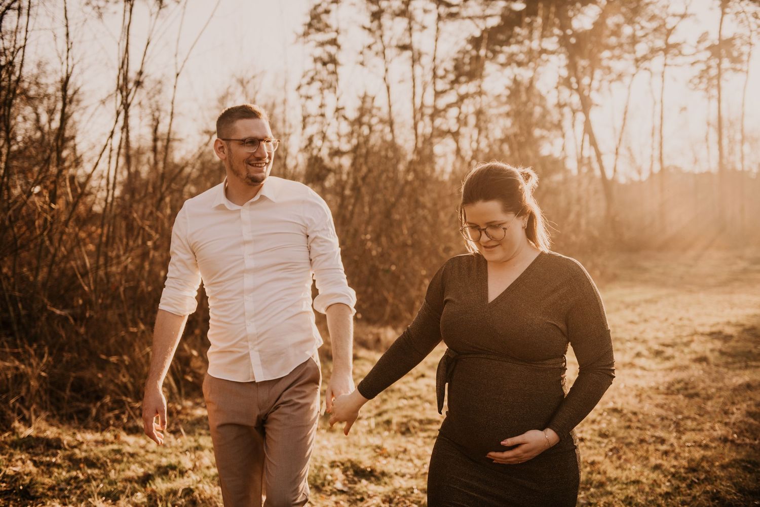 Sunset maternity photoshoot in a wooded outdoor setting.