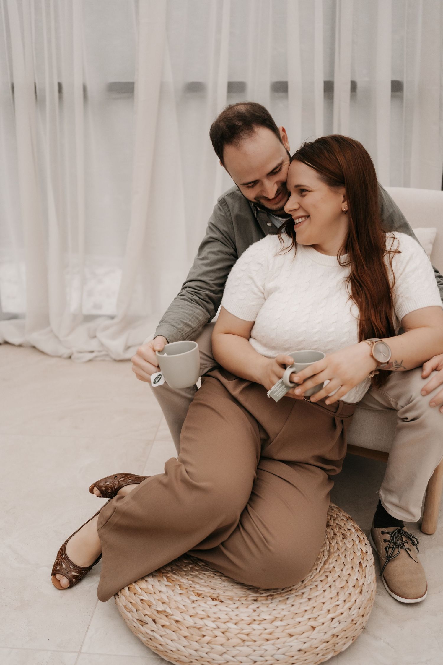 Couple sharing tender moment while sitting on woven floor cushion.