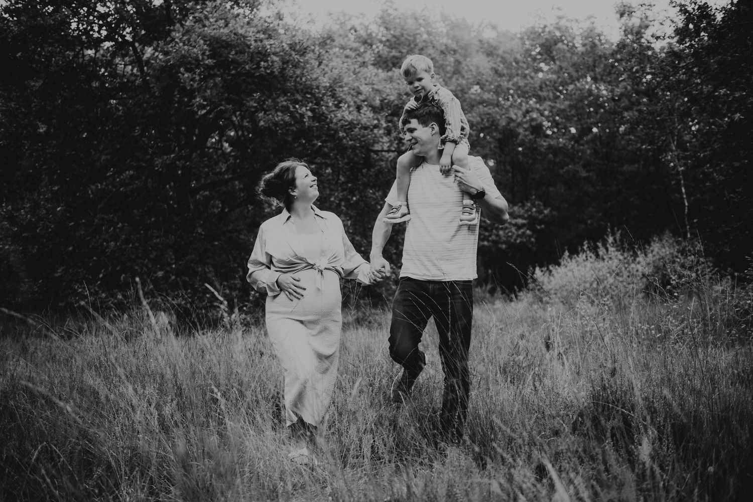 A series of black and white photos showing a couple walking together in a grassy outdoor setting.
