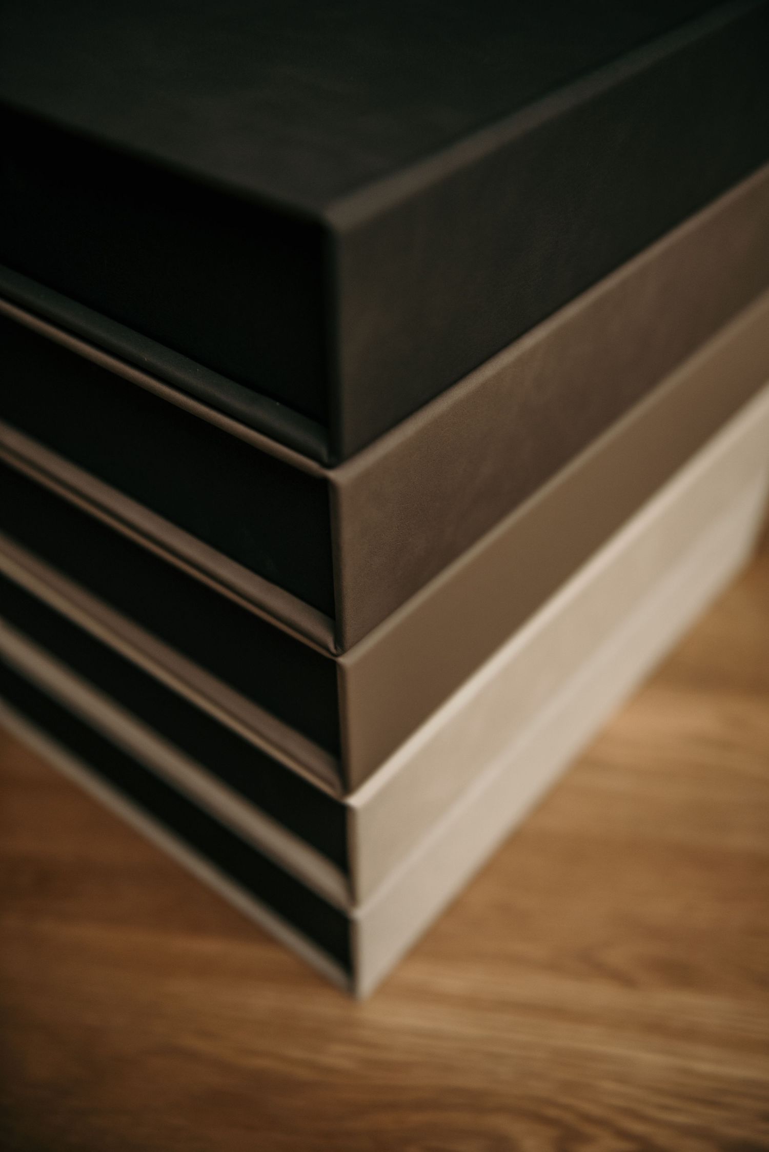 Multiple black leather photo albums stacked on a wooden surface with dramatic lighting.