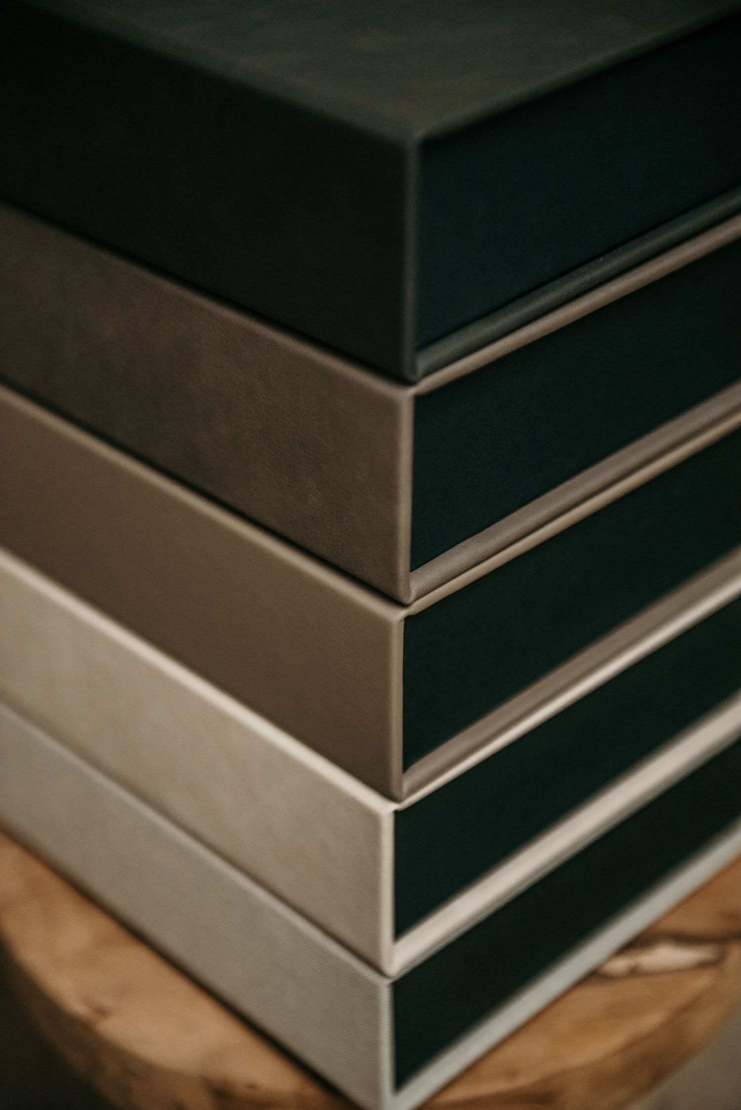 Stack of elegant black photo albums with metallic edges on wooden surface.