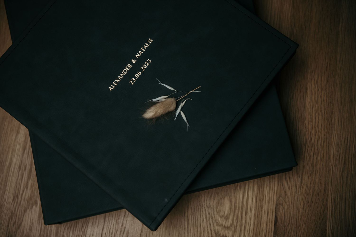 Black wedding photo albums arranged on dark wooden surface.