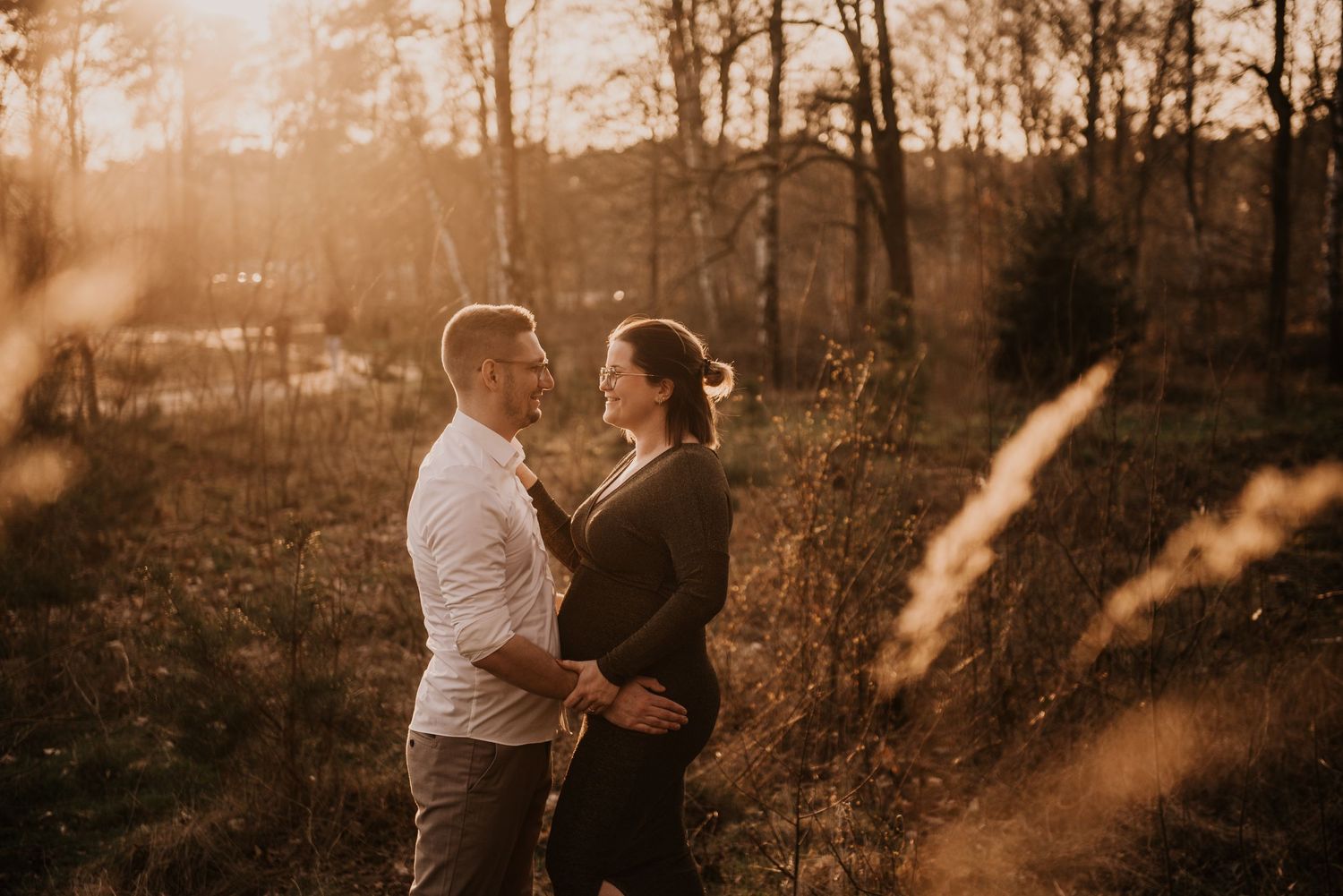 Warm sunset light filters through trees as couple walks in nature.