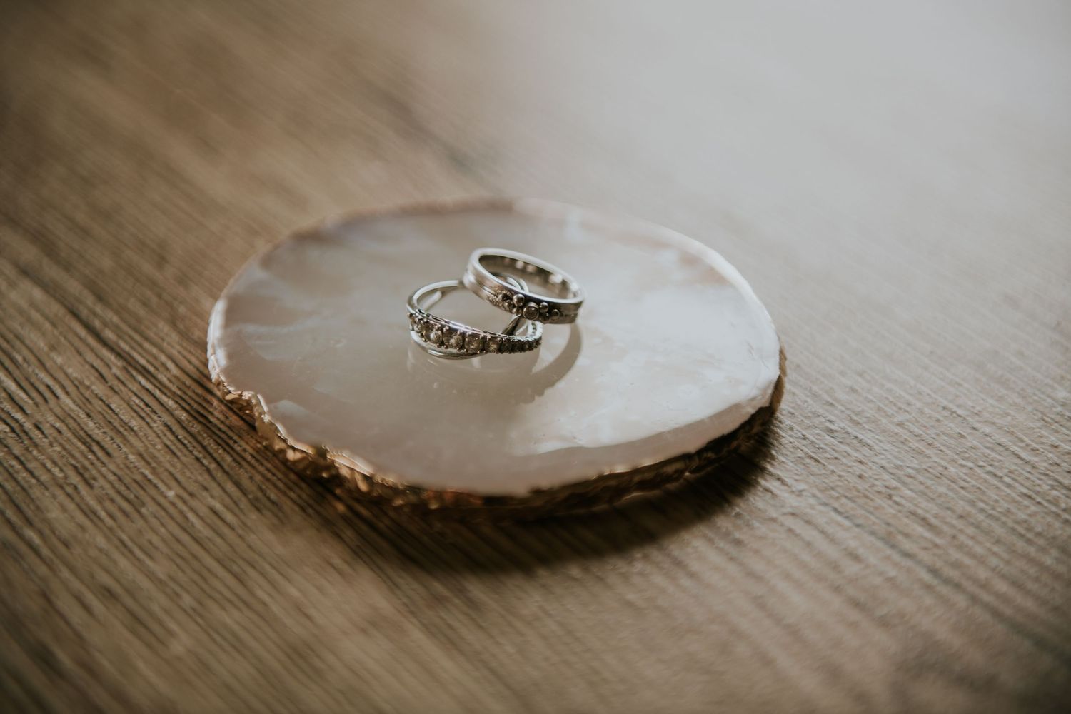 Wedding rings artistically arranged on wooden surface in warm lighting.