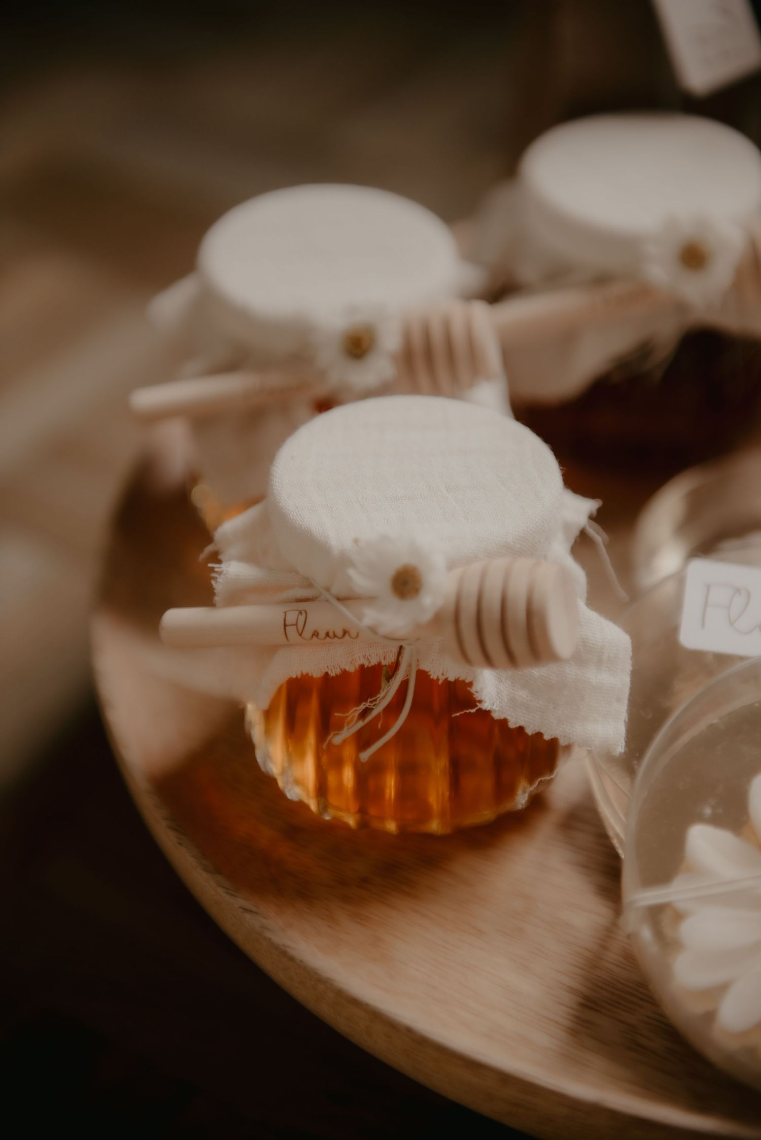 Honey jars with decorative lids arranged on a wooden surface in warm lighting.