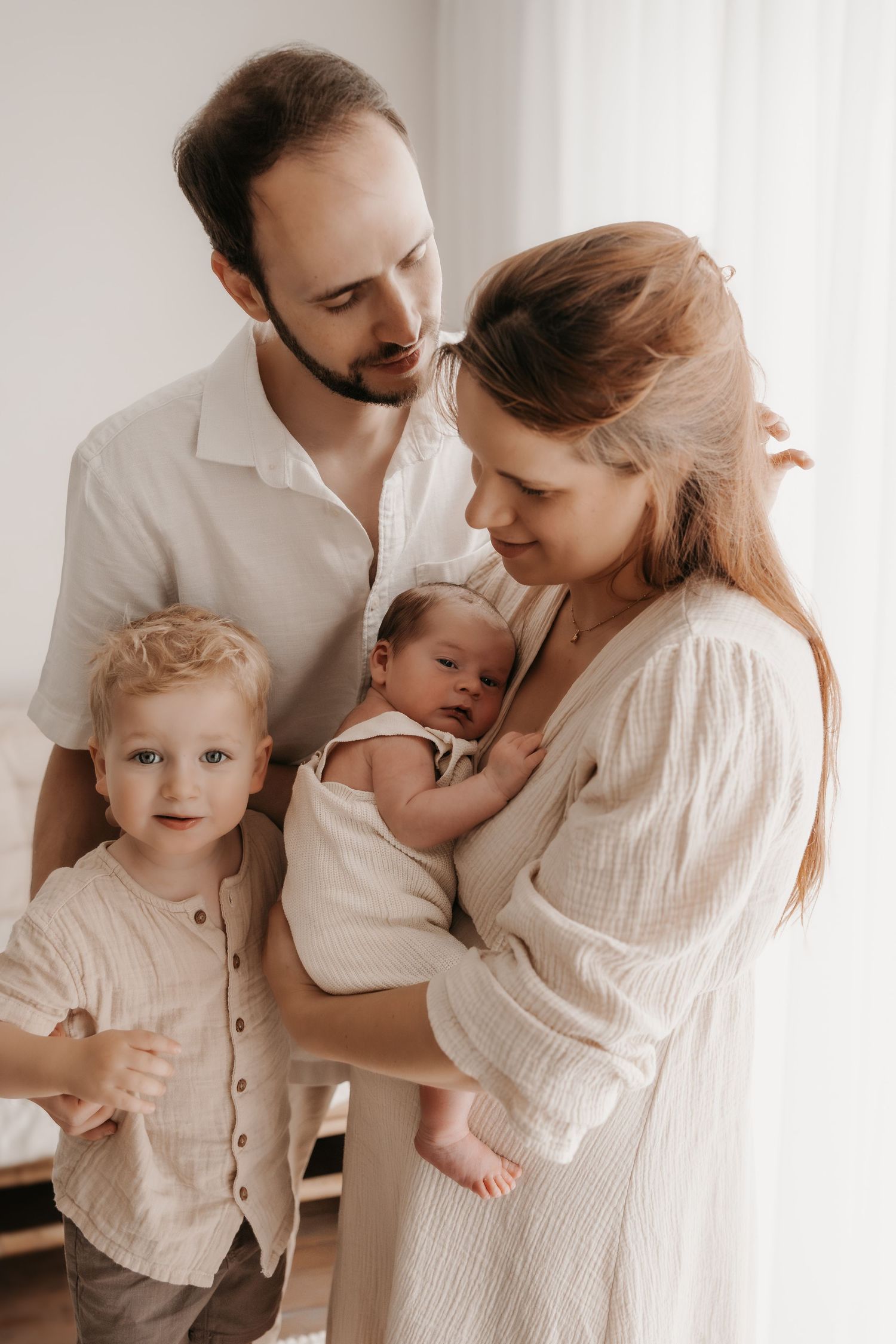 Family portrait series in soft white tones capturing loving interactions between parents and young children.