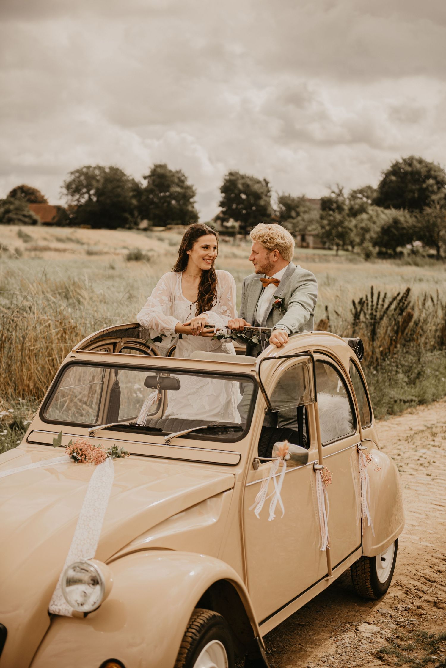 Vintage beige convertible car decorated for a wedding celebration on a country road.