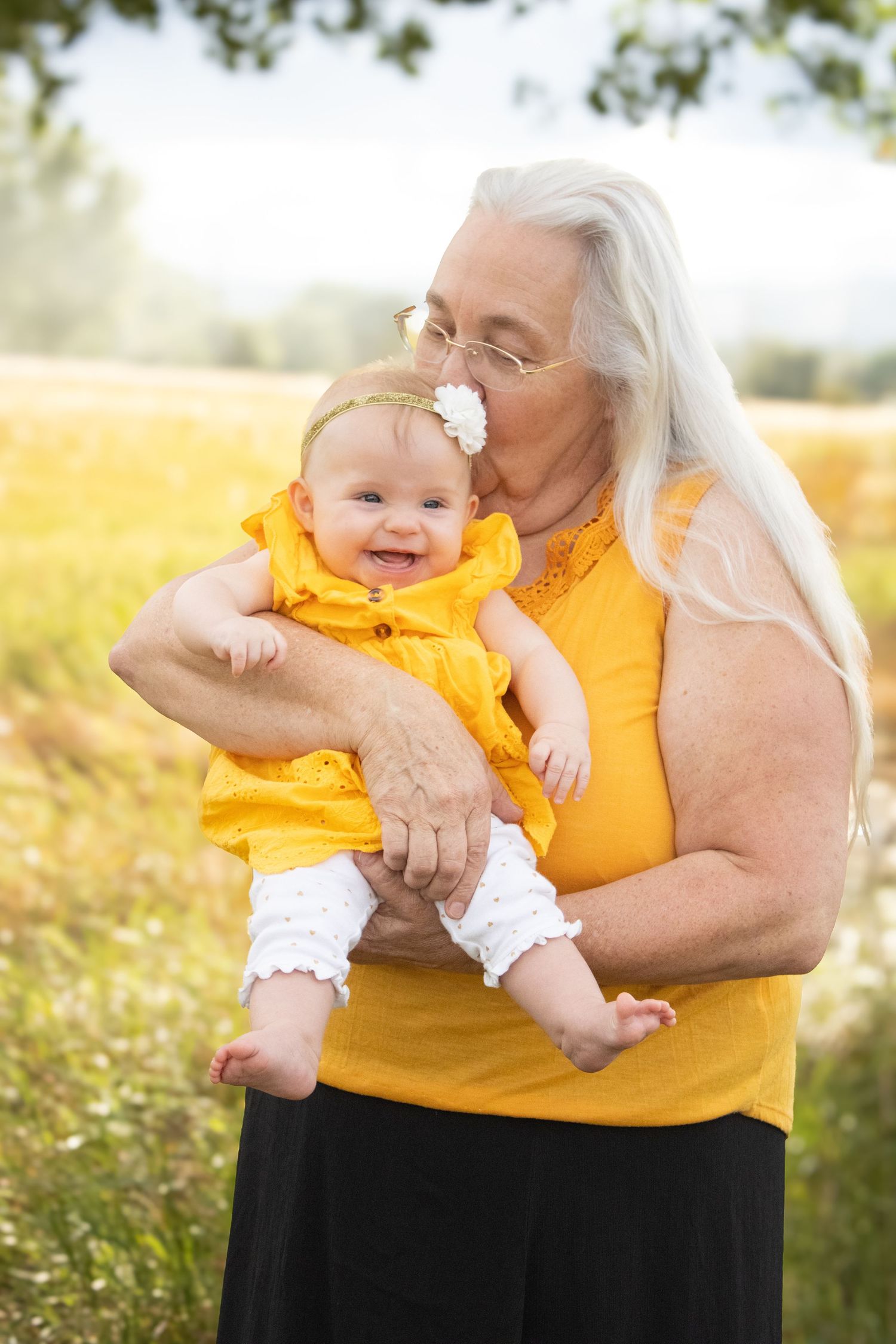 A tender moment shared between generations in matching yellow outfits against a sunlit meadow background.