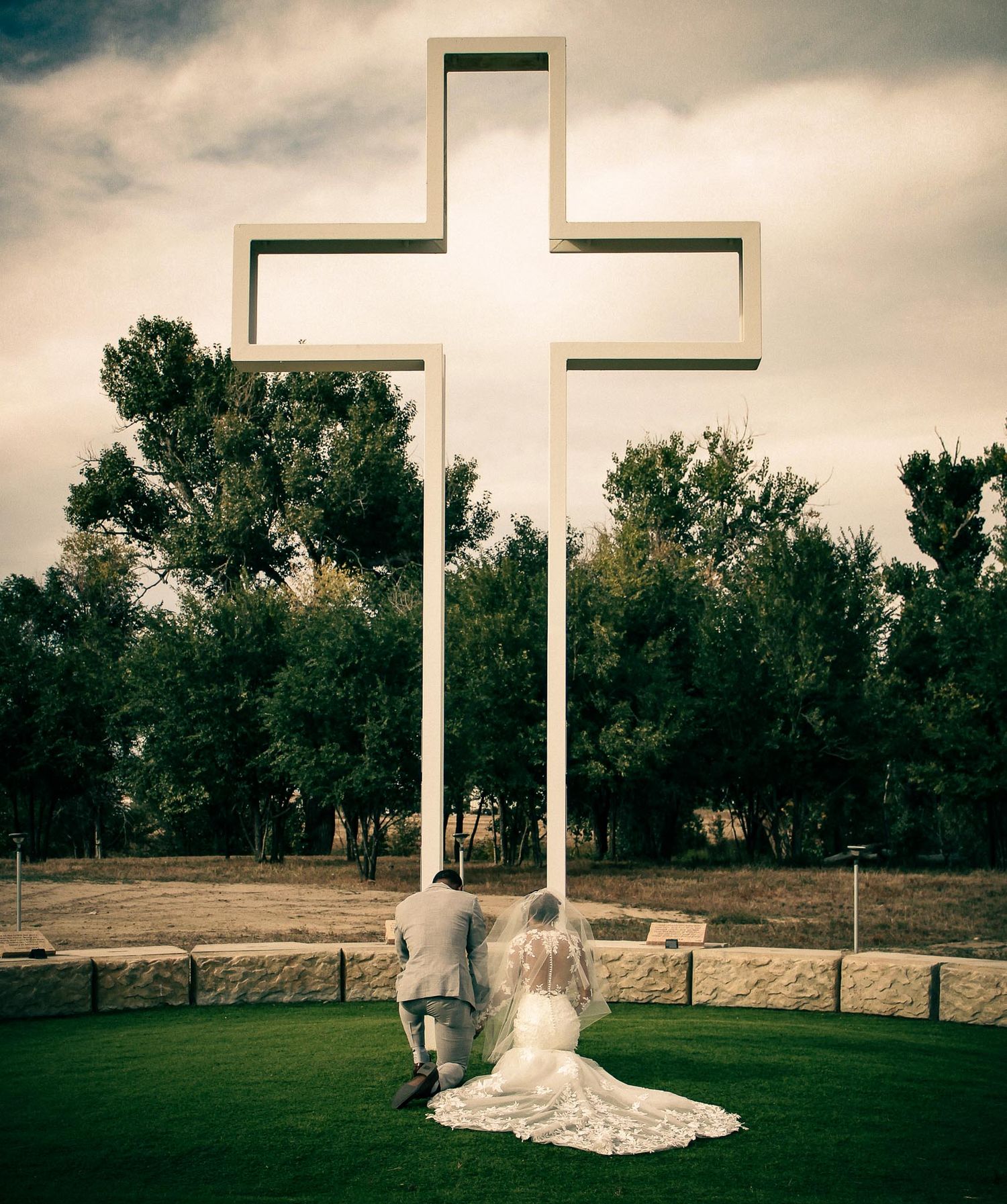 White crosses stand tall against a dramatic cloudy sky during an outdoor wedding ceremony.