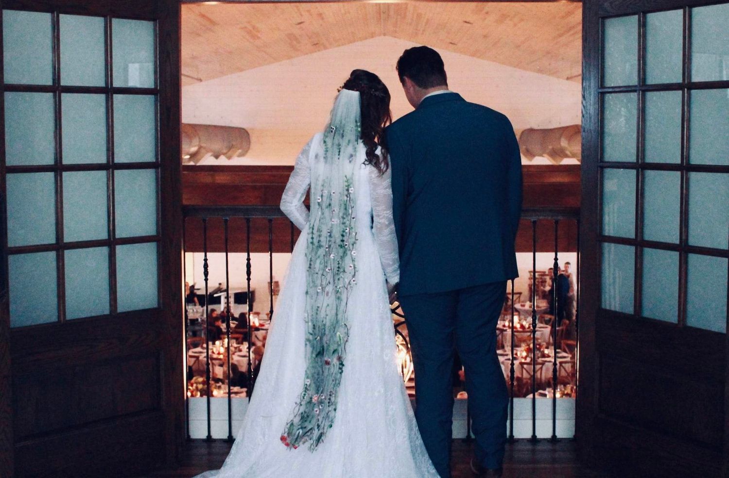 Wedding couple silhouetted against window view in intimate ceremony setting.