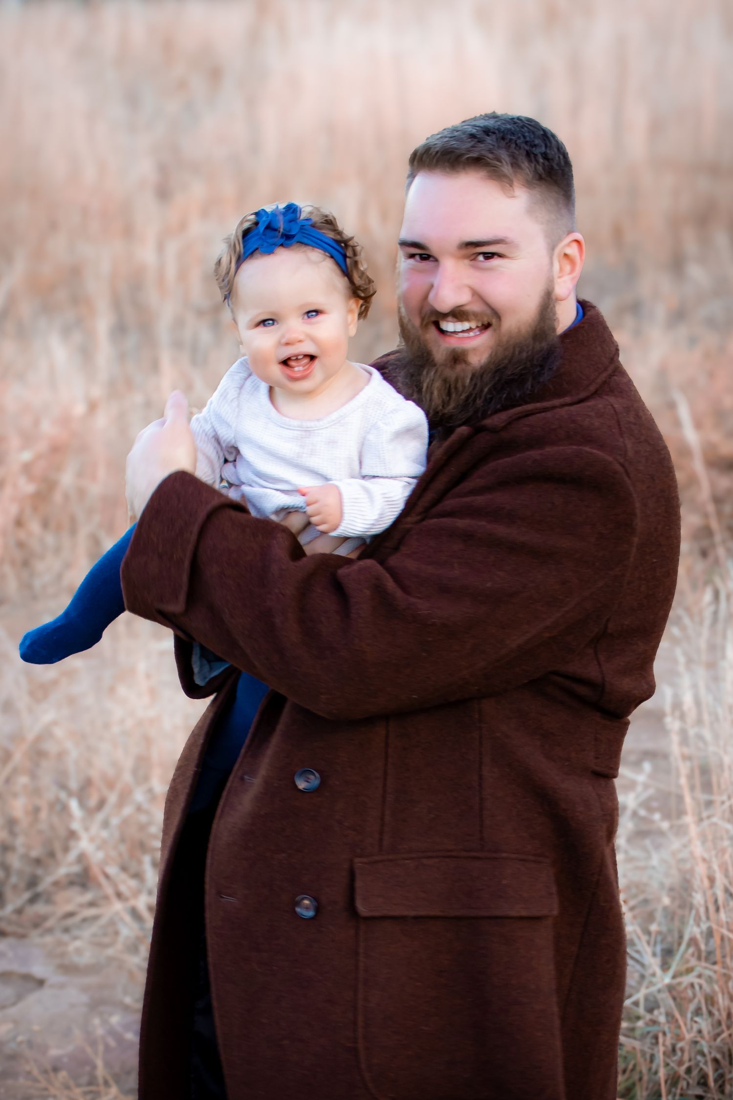 A sequence of playful moments captured in a brown field as a child in white clothing is held and swung by someone in a brown coat.