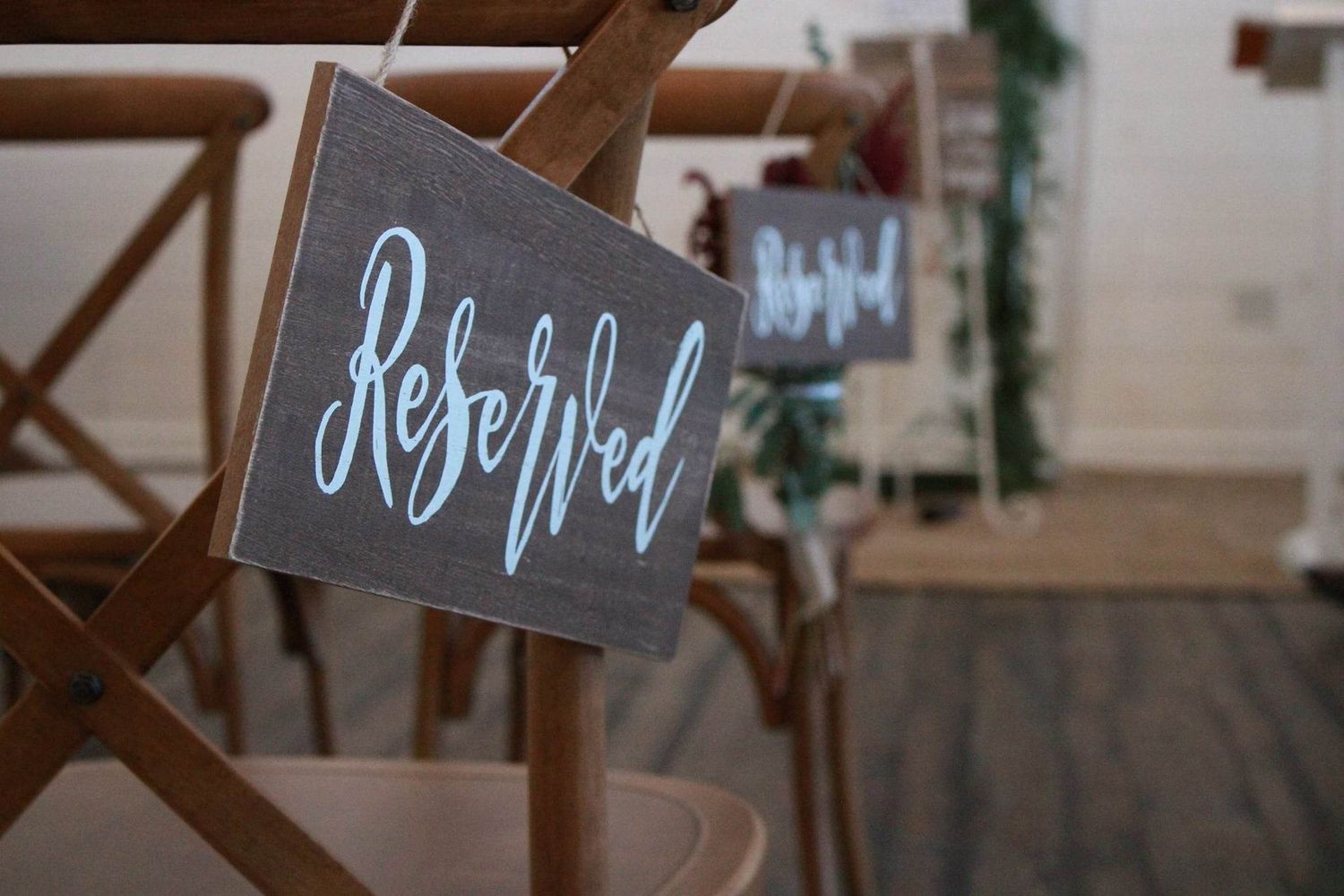 Handwritten 'Reserved' sign hanging on wooden chair at wedding venue.