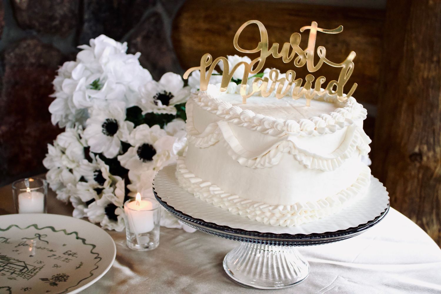 Elegant white wedding cakes with floral decorations displayed on glass stands at reception.