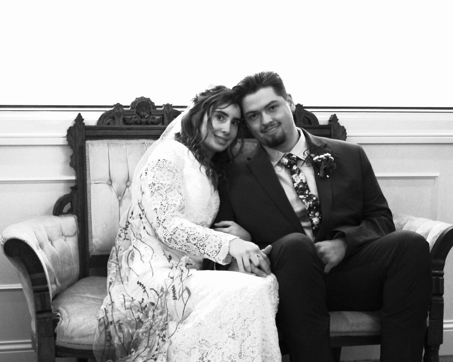 Black and white wedding portrait on vintage sofa with elegant decor.