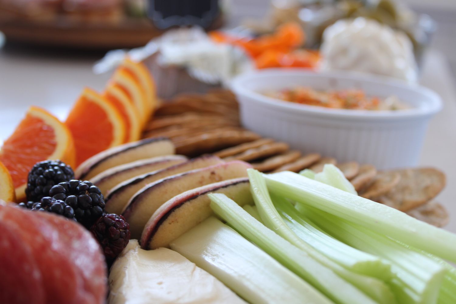 Fresh veggie and fruit platter with celery, oranges, and dips for entertaining.