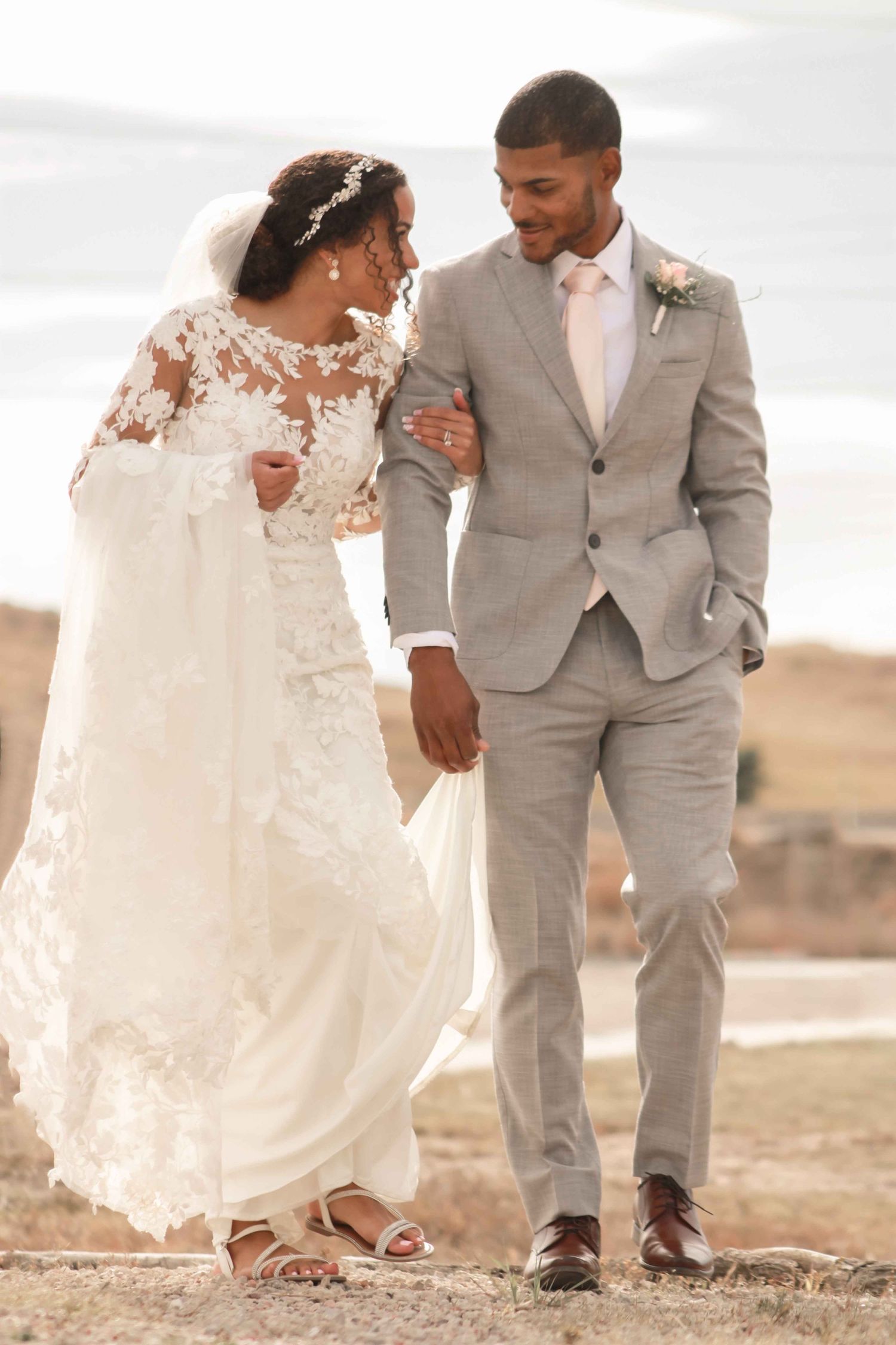 A couple shares a romantic moment on their wedding day in a desert landscape.