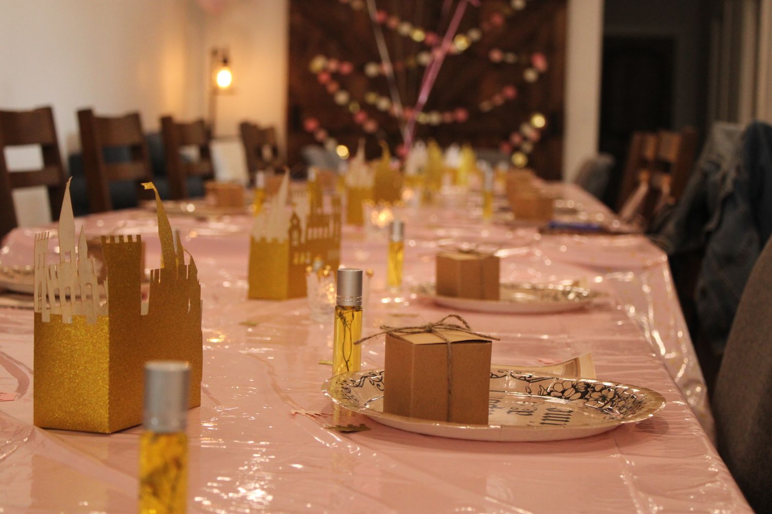 Elegant party table setting with pink tablecloth and decorative gift boxes.