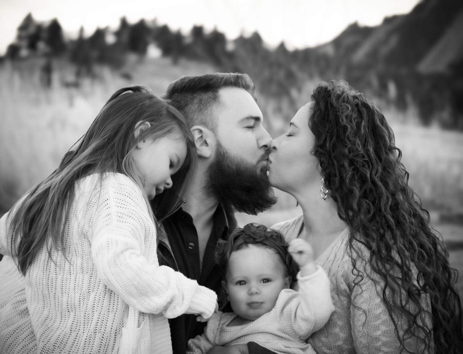 A collection of five black and white romantic photos showing tender moments between a couple and their baby.