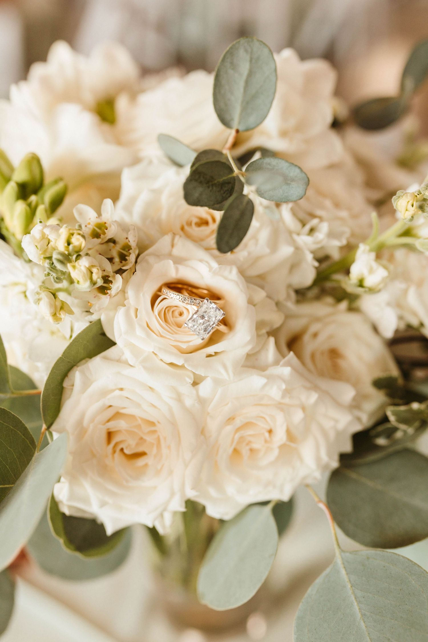 Elegant cream roses and soft eucalyptus leaves create a romantic wedding floral arrangement in natural light.