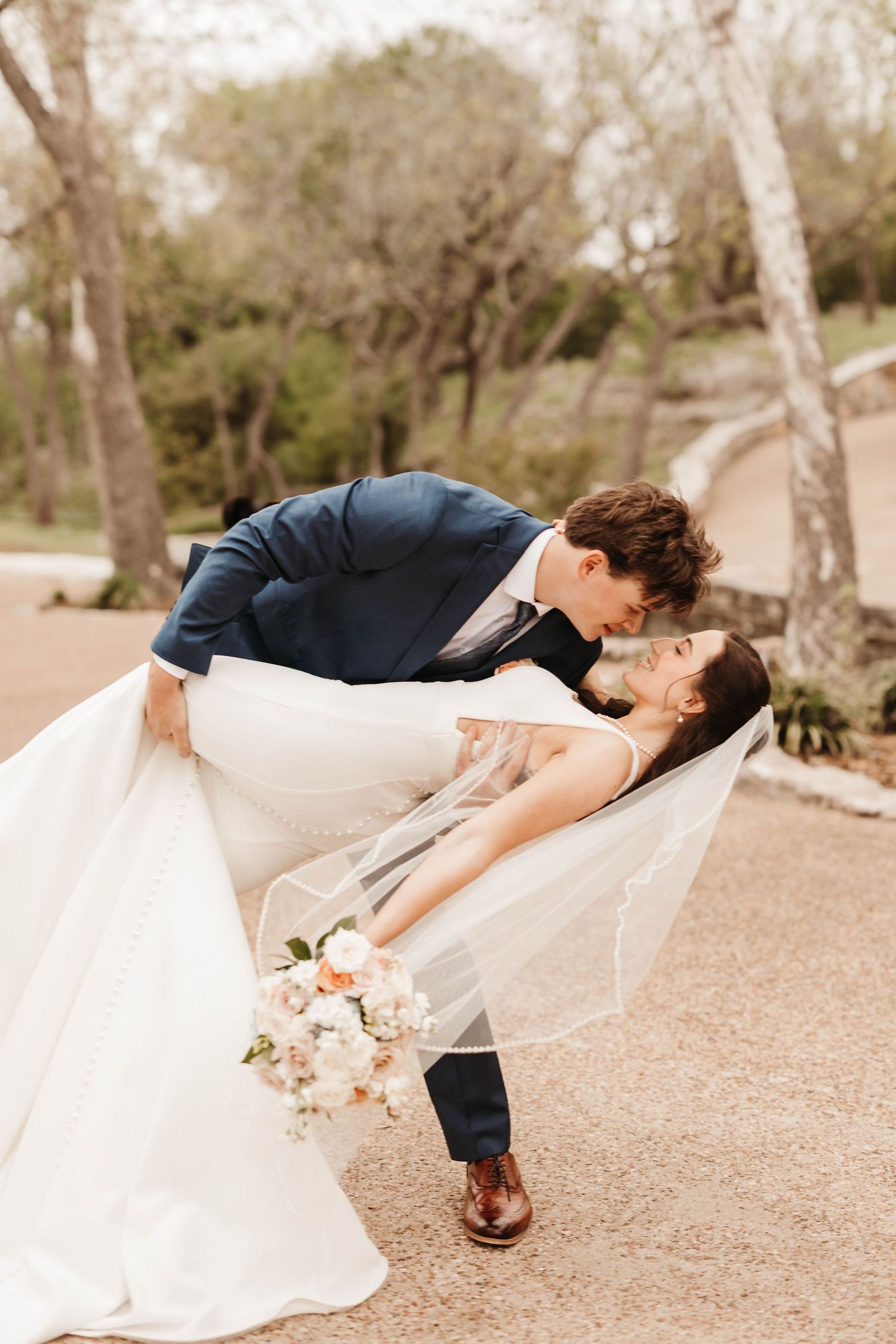 A romantic wedding photo shows a couple in a dramatic dip pose, with the bride holding a peach floral bouquet.