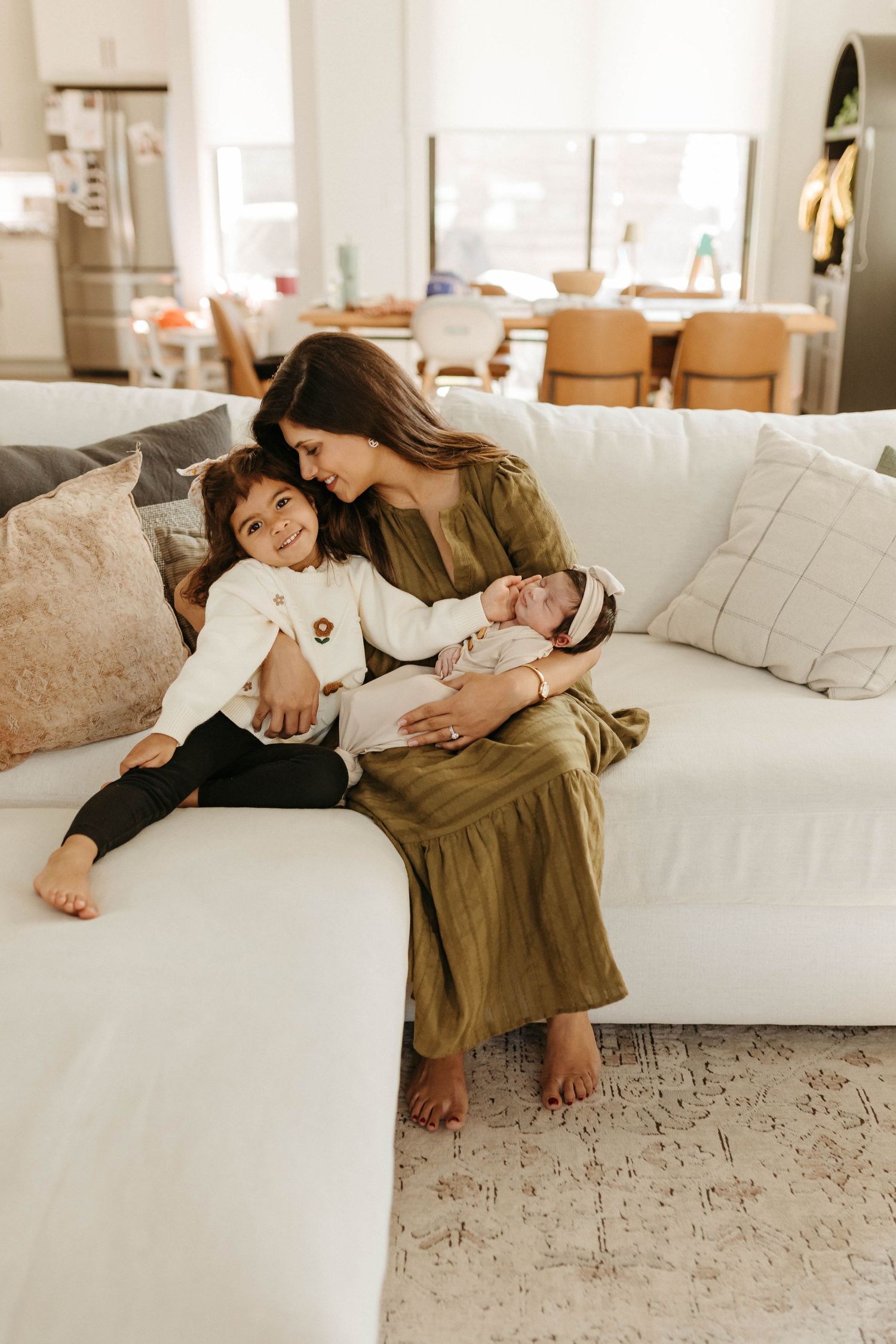 A tender moment shared between family members relaxing together on a white couch in a bright, modern living room.