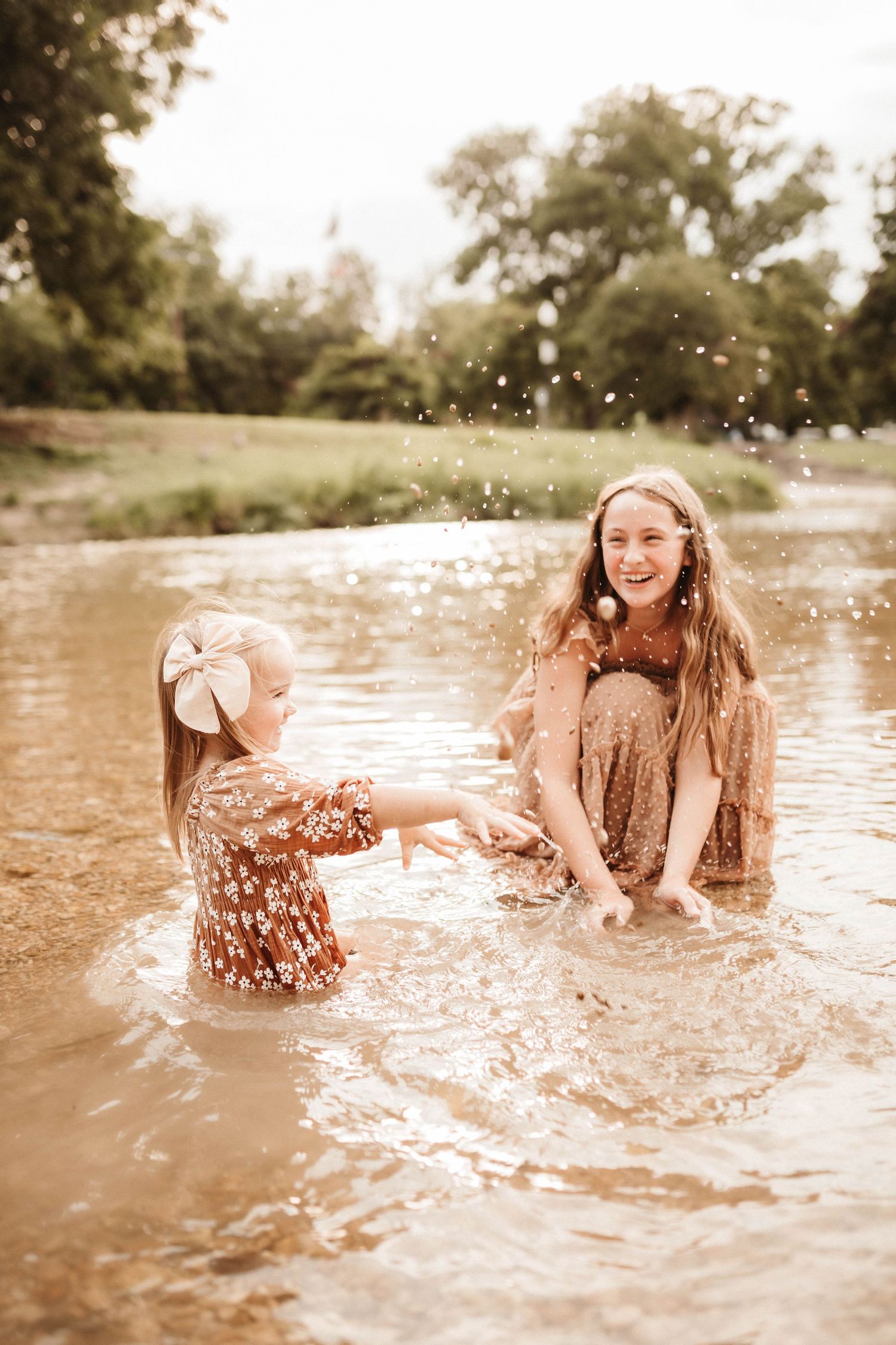 Two friends splash and play together in shallow muddy water on a warm summer day creating joyful moments.