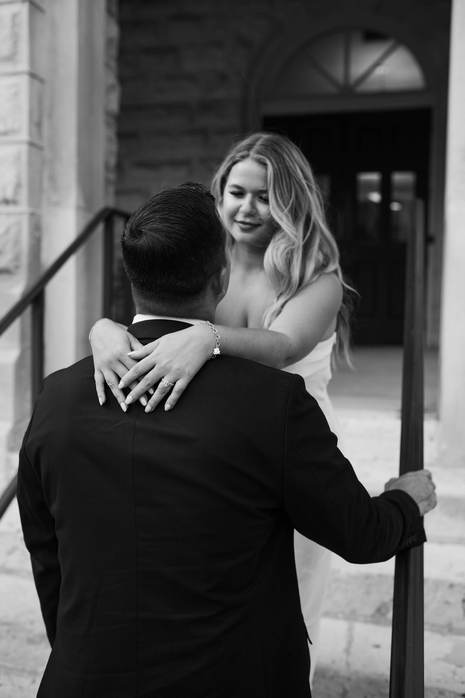 Black and white photo of couples embracing and kissing in a romantic outdoor setting with architectural columns.