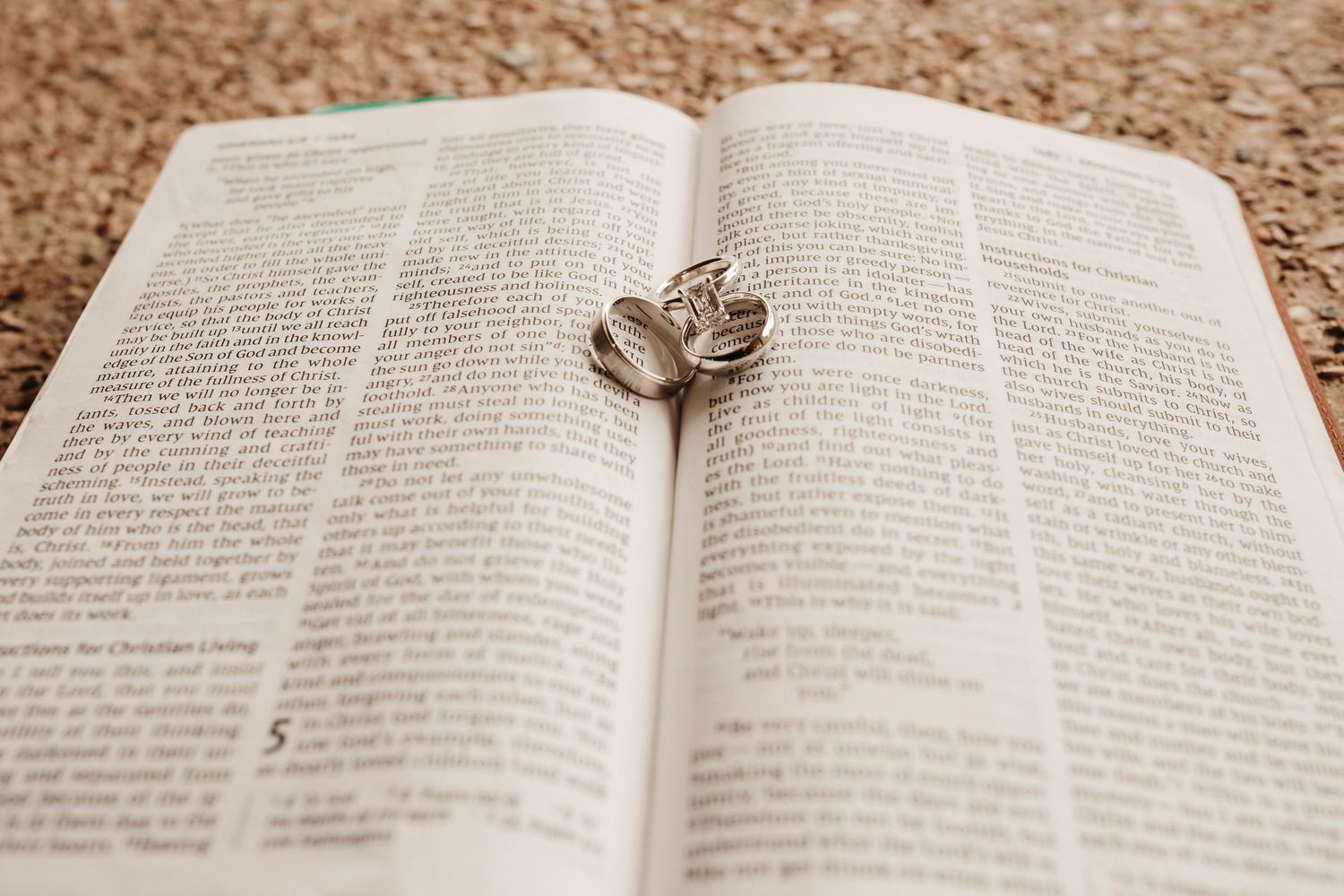Open Bible pages with text visible on textured beige carpet or rug surface.