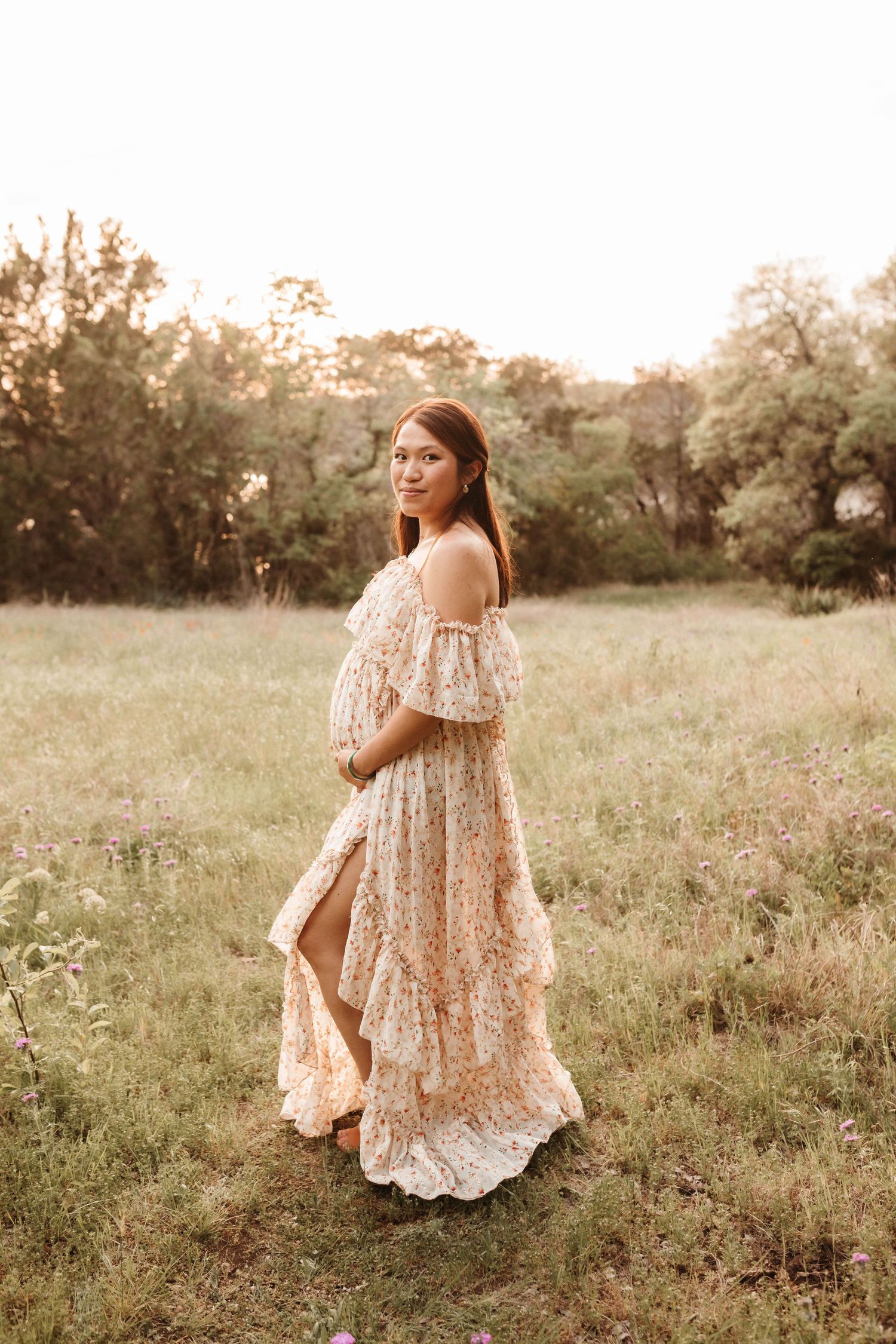 A person in a flowy lace dress walks through a sunlit meadow during golden hour.