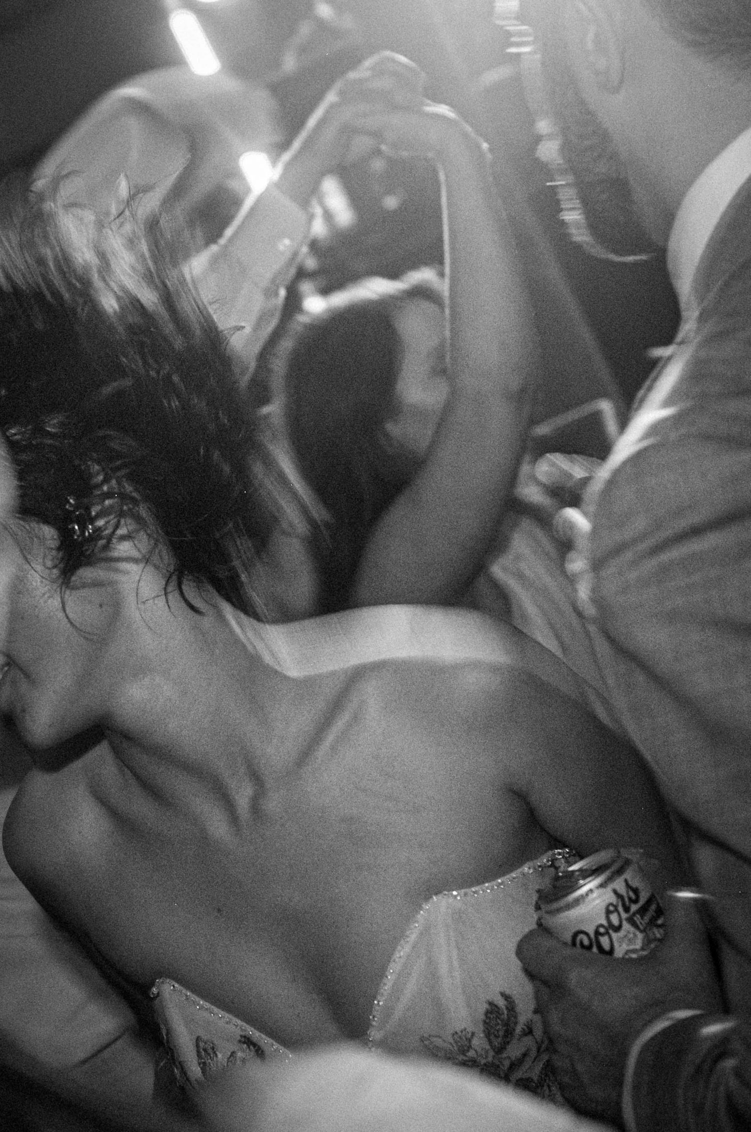 Black and white photo of wedding guests dancing closely at a lively reception party.