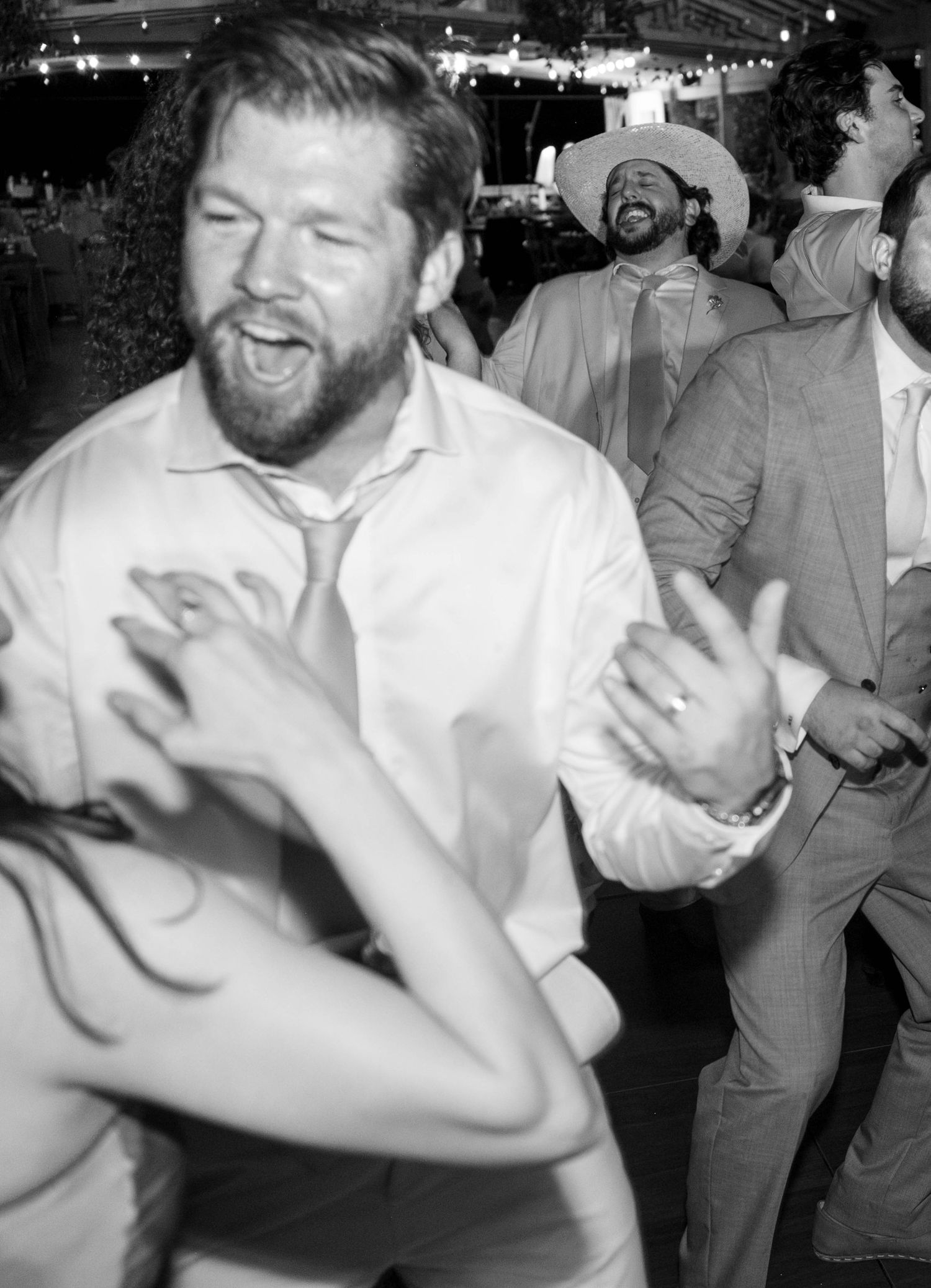 Black and white photo of guests dancing energetically at lively wedding reception.