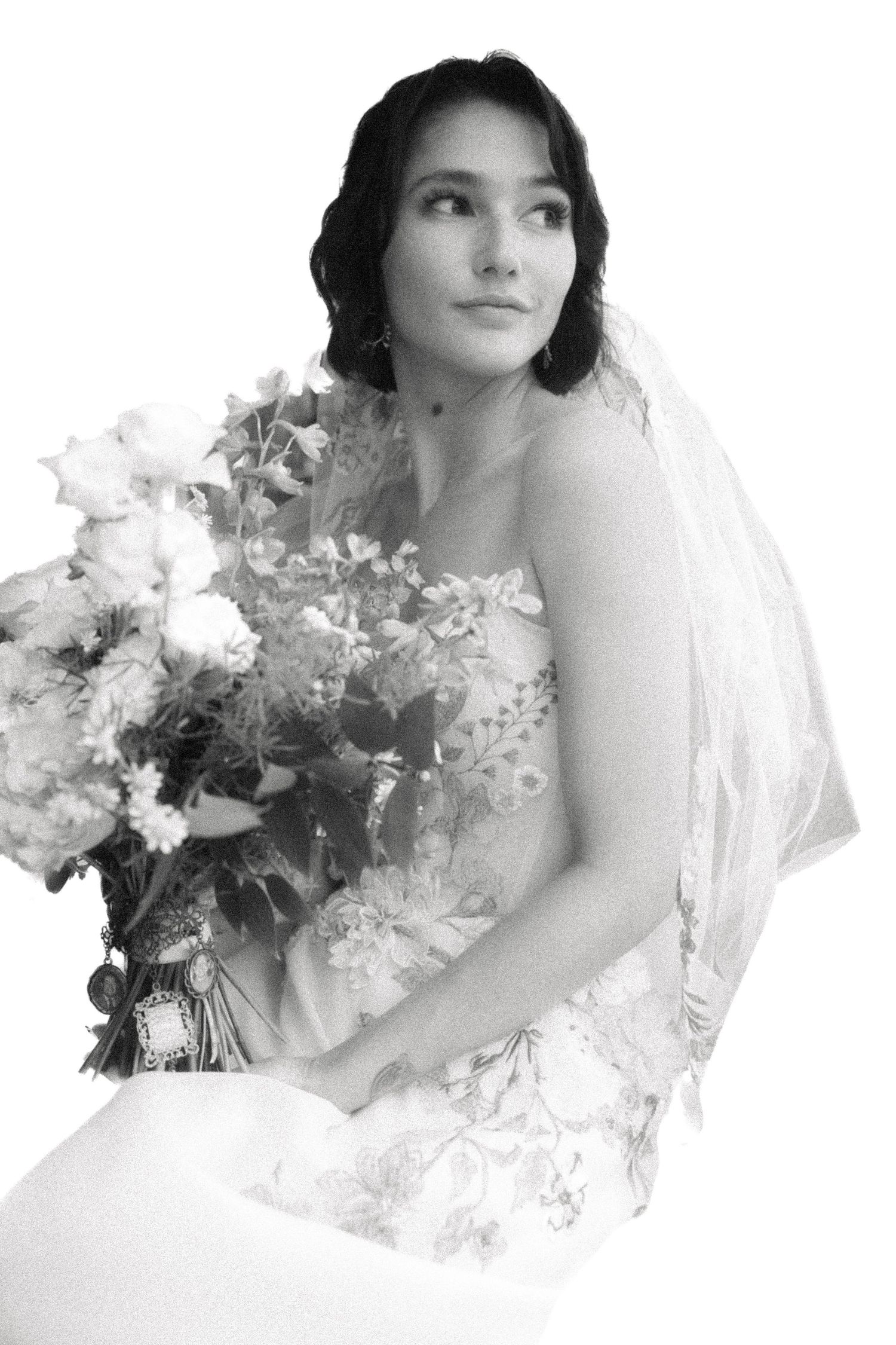 Black and white bridal portrait with woman holding bouquet and wearing veil.