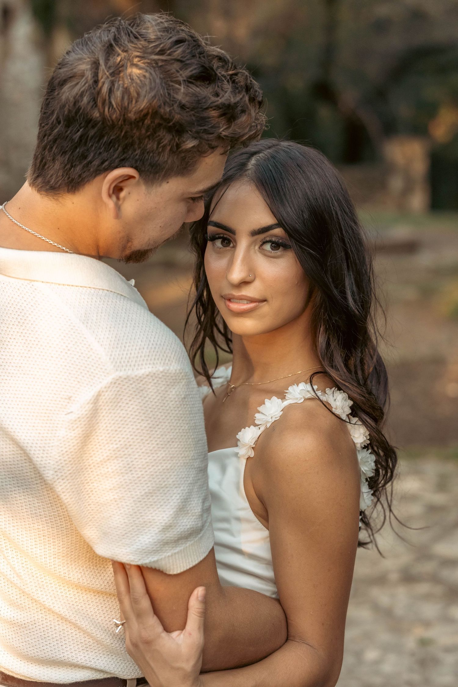 Close romantic portrait of couple embracing in warm golden outdoor light.