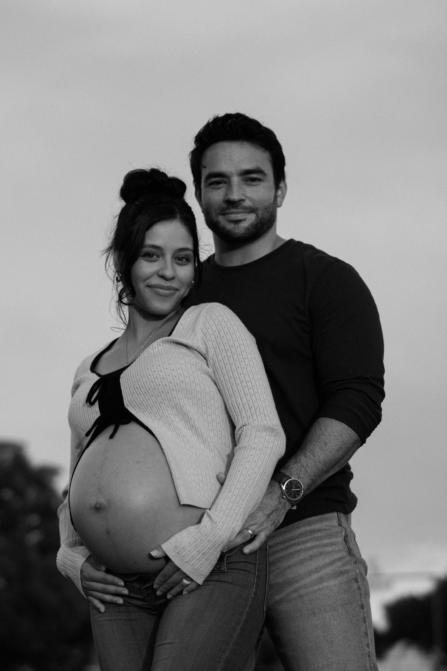 A series of black and white maternity photos showing a couple embracing and celebrating pregnancy.