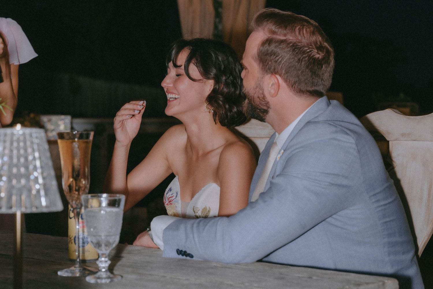 Bride and groom smiling and relaxing together at their wedding reception dinner table.