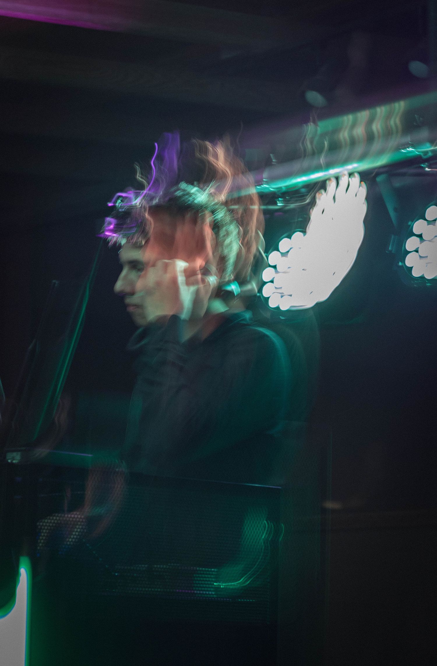 Musician performing on stage with colorful neon lights creating a vibrant motion blur effect in a dark venue.