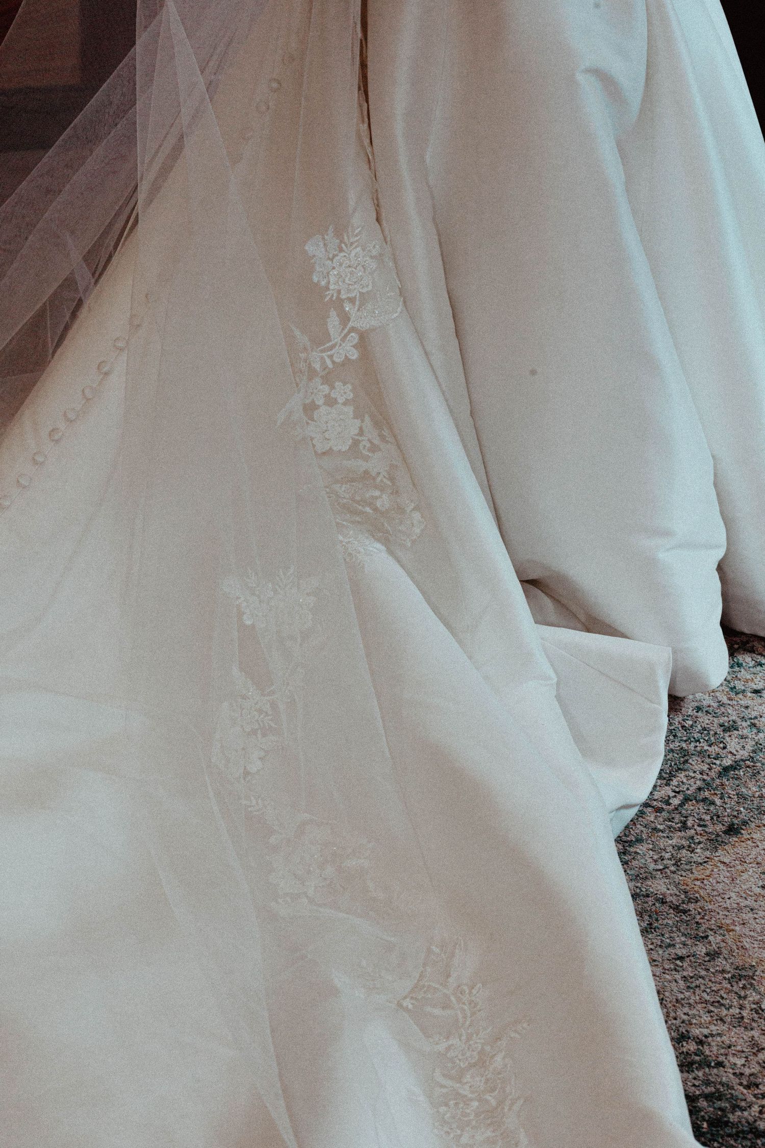 Close-up of elegant white wedding dress train featuring delicate floral lace embroidery detail.