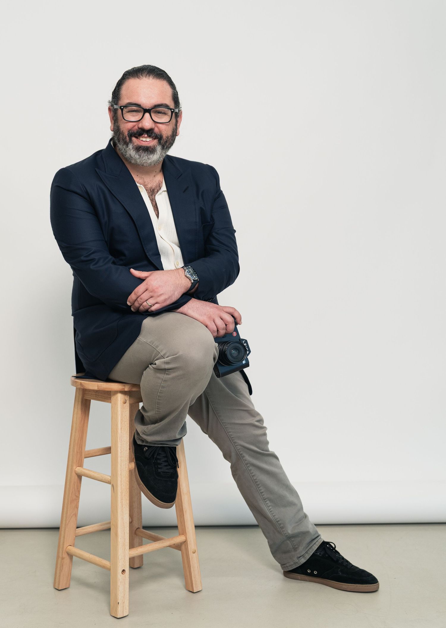 Professional portrait series showing someone seated on a wooden stool against a white background in business attire.